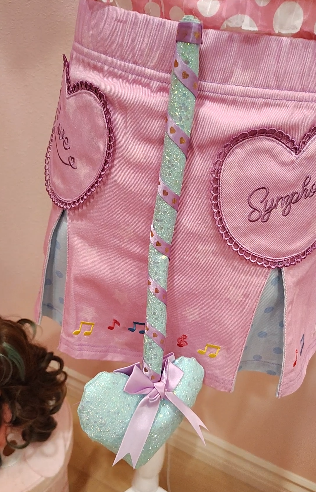 Purple skirt with heart designs showcasing a sparkly blue devil tail with heart prong wrapped in purple ribbon.