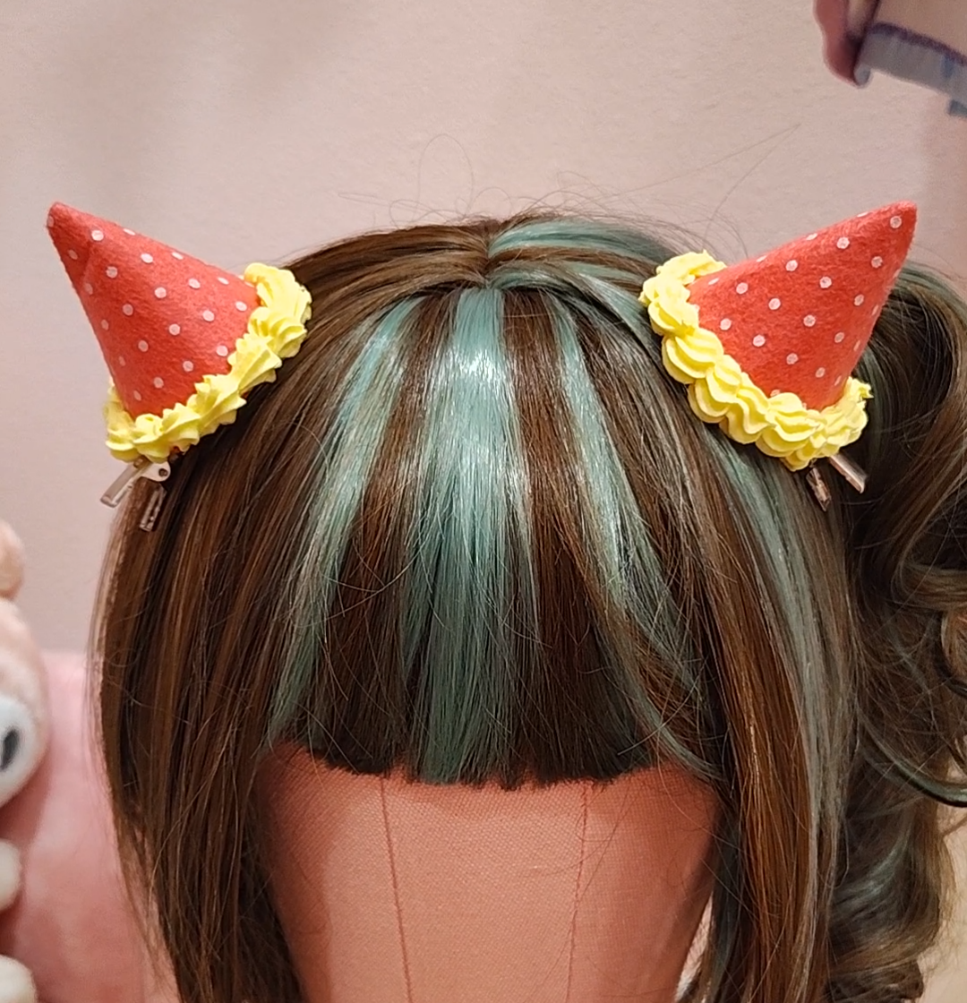 Mannequin head with colorful hair and devil horn hair clips on a pink background