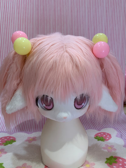 A pink and yellow toy ball bobble attached to a mannequin head with a wig.