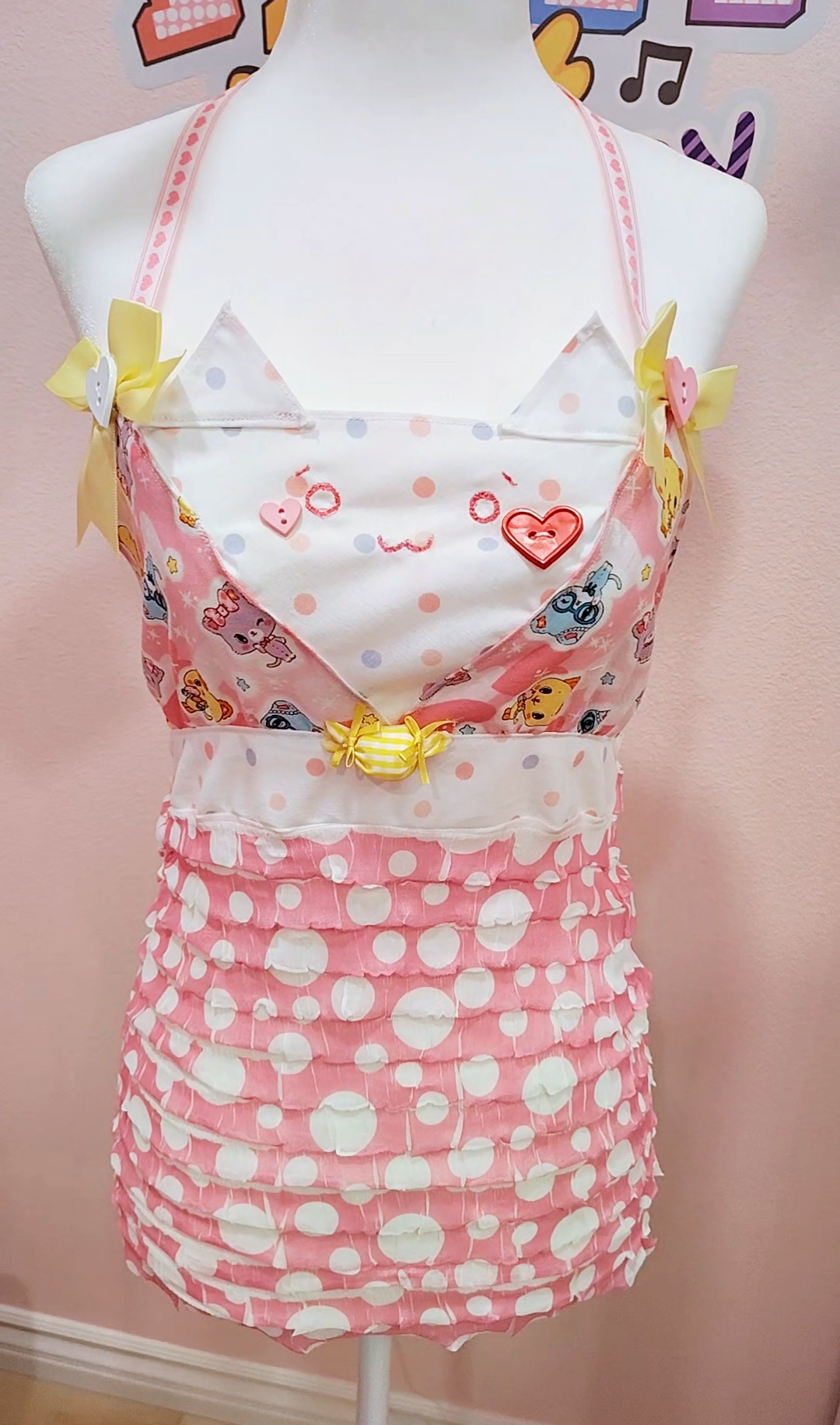 dress with polka dot skirt and cartoon character top on a mannequin against a pink background.