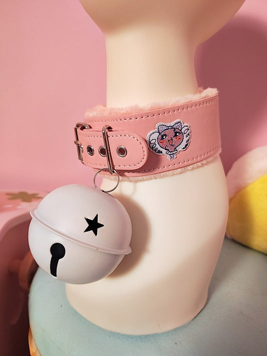 Pink collar with a bell on a mannequin against a pink background