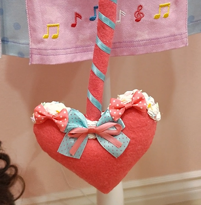 Detail of devil tail accessory tip showcasing heart shape, decoden cream, and pink and blue ribbons.