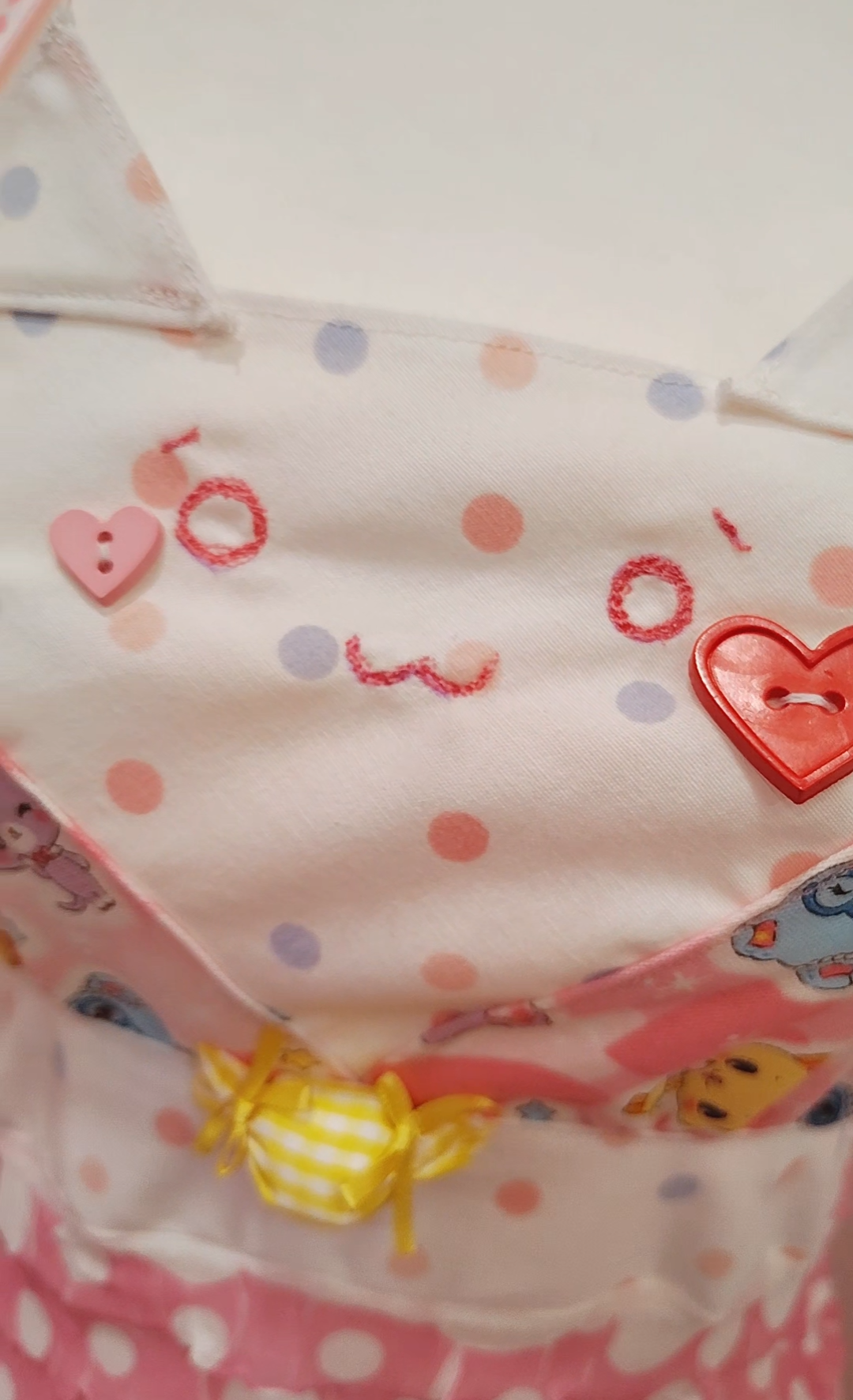 Detail of cat-themed dress with polka dots and heart designs on a colorful background