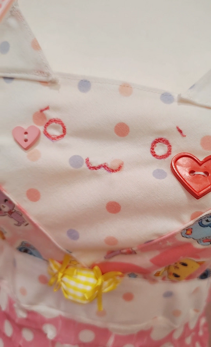 Detail of cat-themed dress with polka dots and heart designs on a colorful background